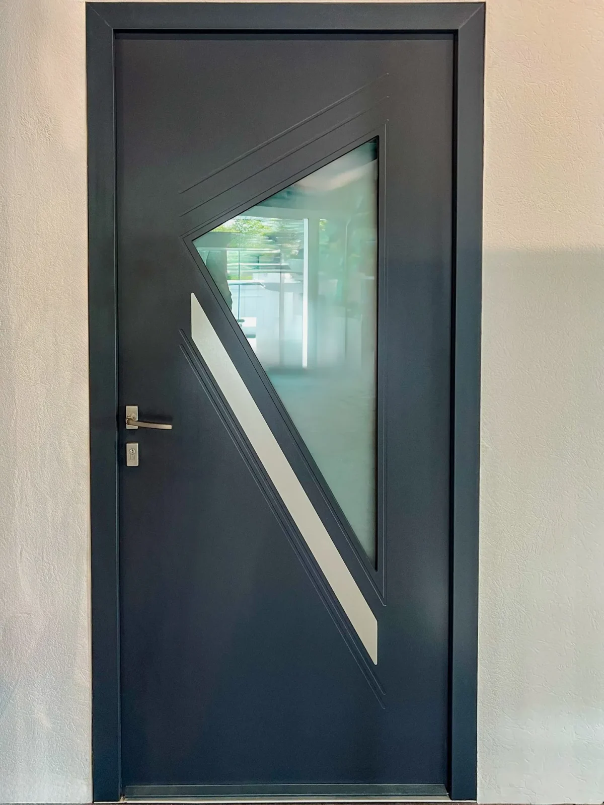Porte d'entrée en aluminium gris anthracite avec vitrage triangulaire, posée par Maison Aubin à Liffré